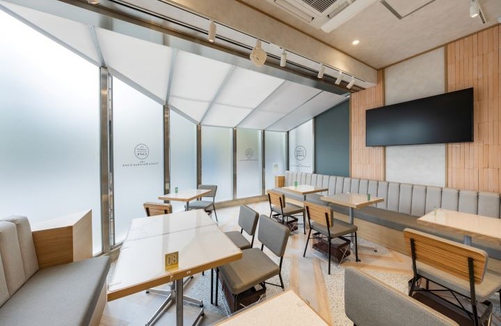 ベンチ席とテーブル、大型モニターを配置したTOWER RECORDS CAFE池袋店の客席