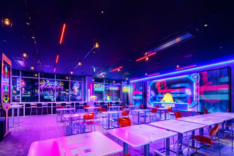 ネオンのグラフィックとカラフルな照明で演出されたnamco TOKYOの飲食スペース